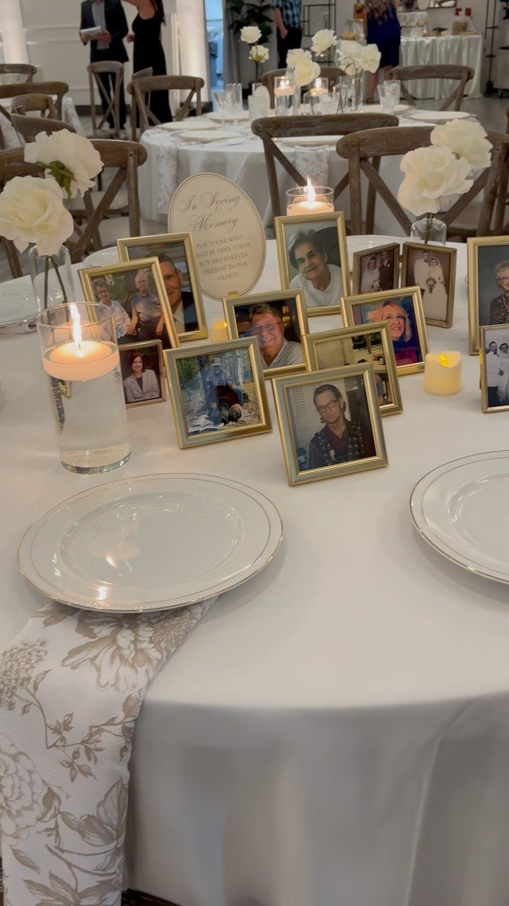 Memory table with framed photographs, white roses, and lit candles on white tablecloth
