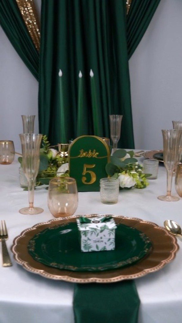 Gold-rimmed plates and cutlery on a white table with dark green accents.