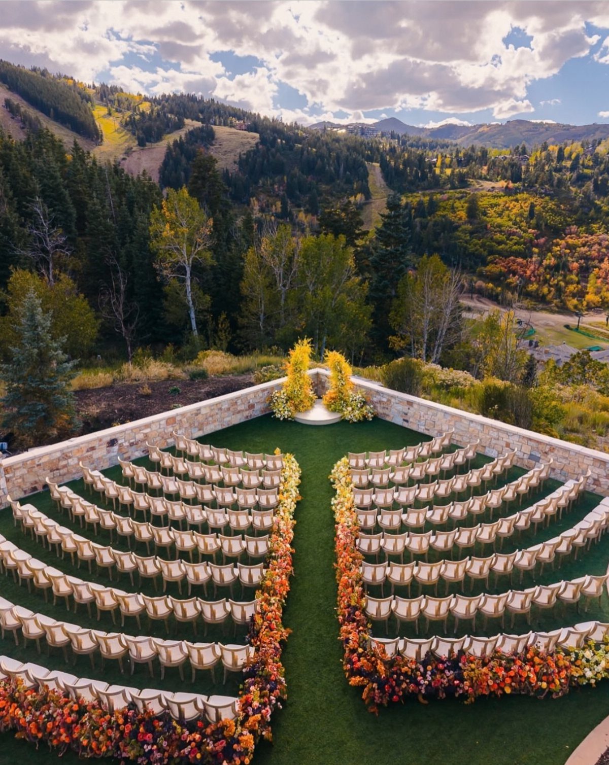 Outdoor wedding ceremony setup with autumn floral borders overlooking a colorful mountain valley