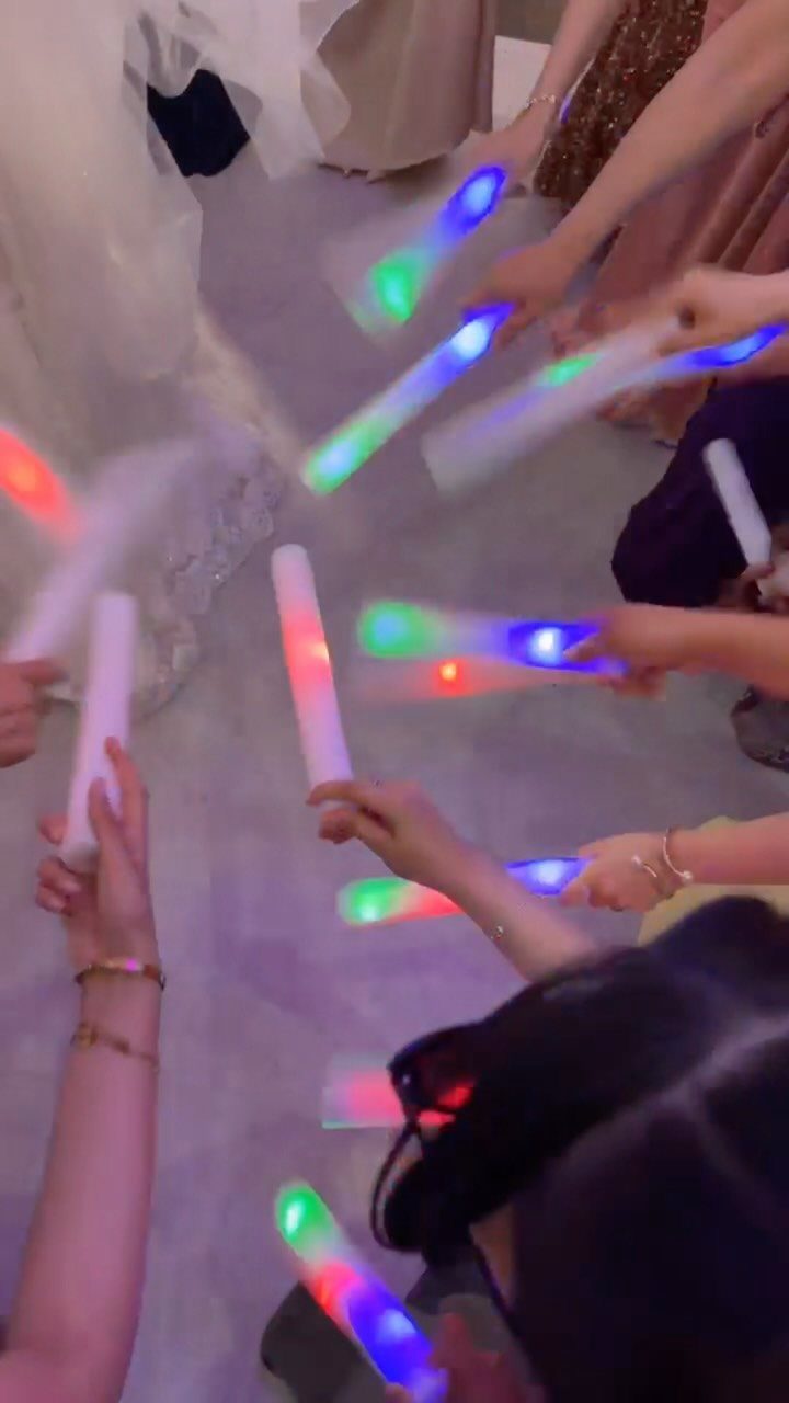 Glowing LED foam sticks held by guests during a dance party celebration.