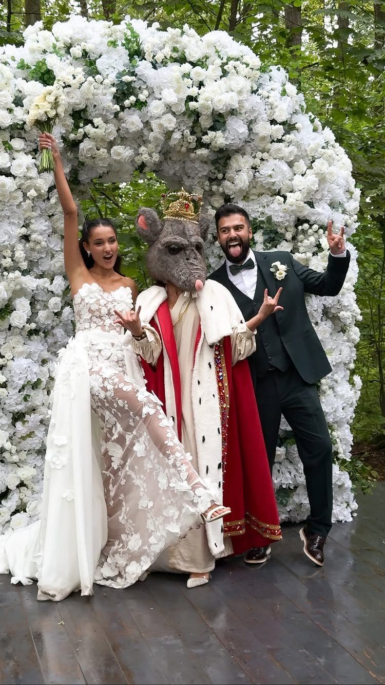 Bride and groom posing with a person in a rat mask and royal cape.