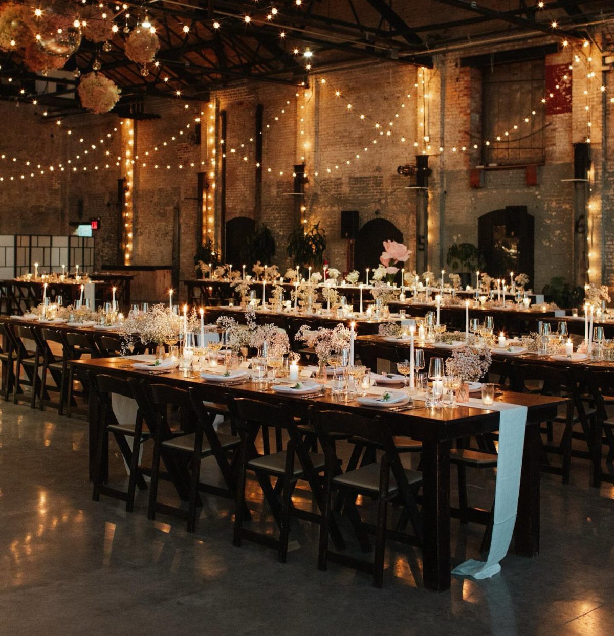 Wedding reception tables with candles and fairy lights in an industrial brick venue