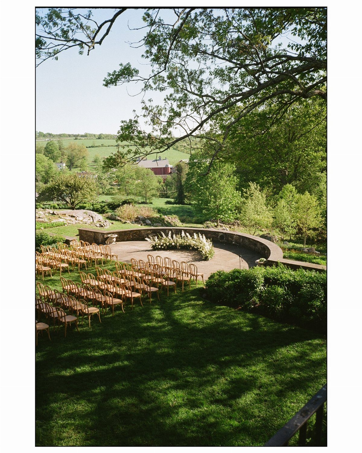 Outdoor wedding ceremony setup with wooden chairs and stone altar in rural landscape