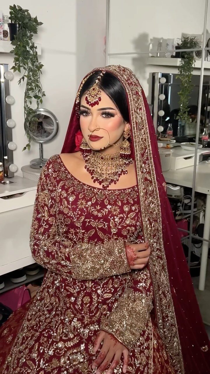 Indian bride in maroon embroidered lehenga with a traditional red dupatta and gold jewellery