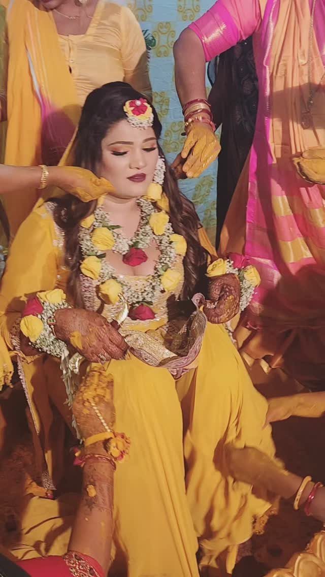 Woman in yellow outfit and floral jewelry during a traditional Haldi ceremony