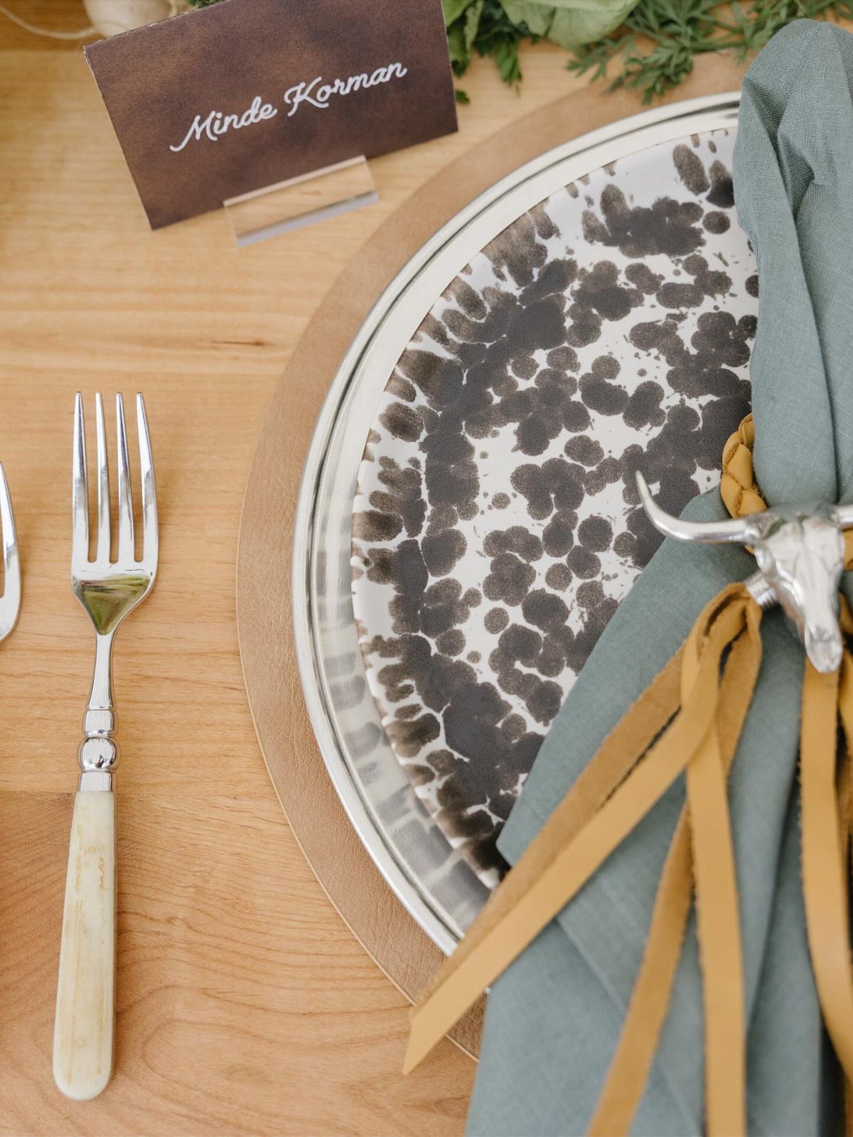 Rustic wedding table setting with speckled plate, leather accents, and a place card.