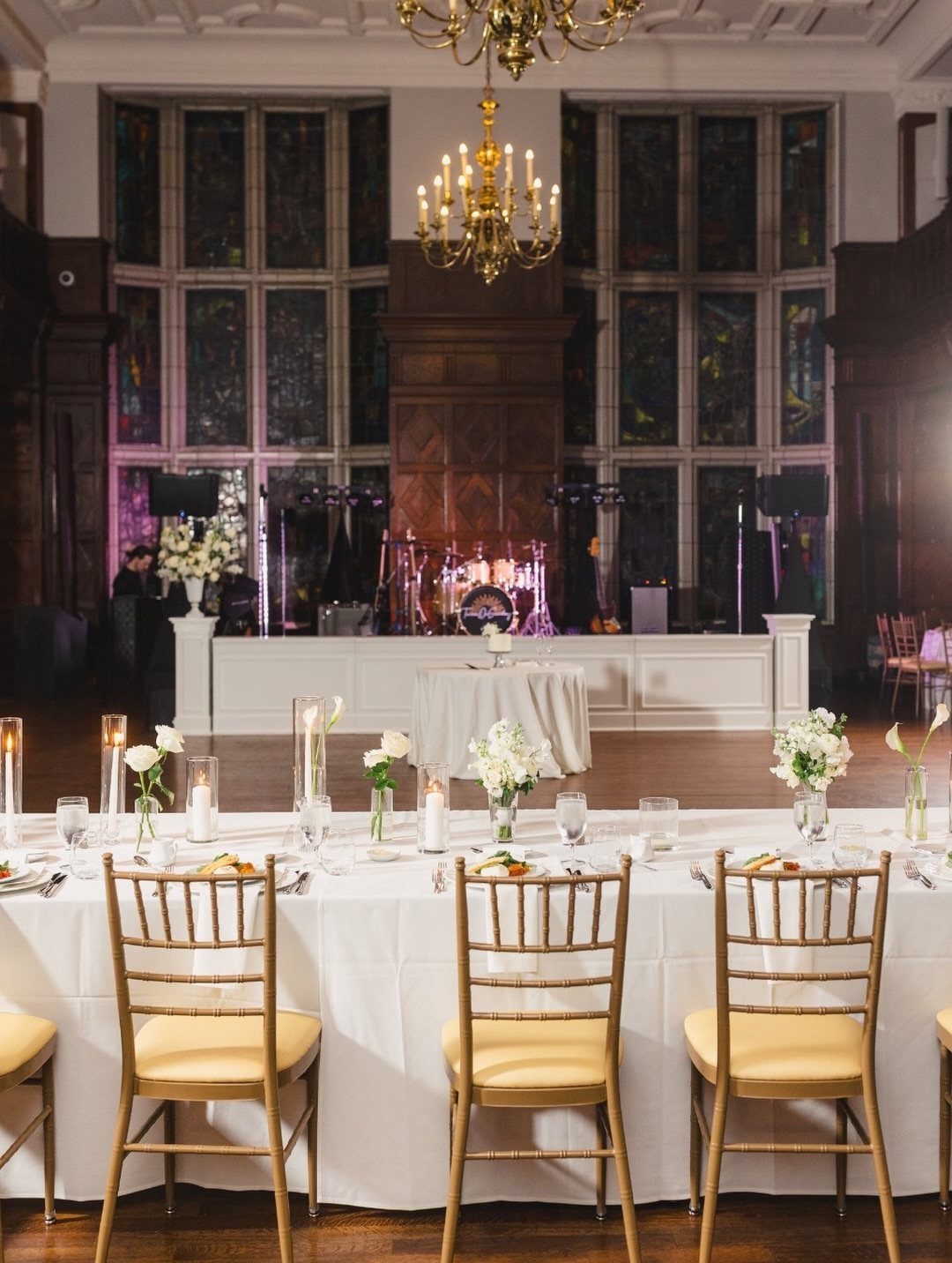 Wedding head table with white linens and gold chairs in an elegant ballroom
