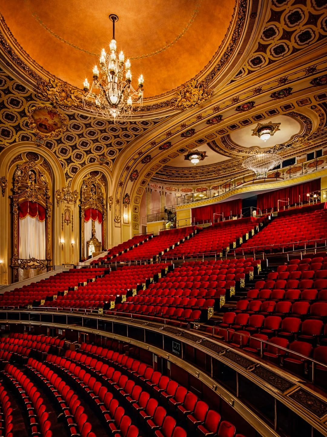 Ornate theater interior with red velvet seating and gold gilded architectural details.