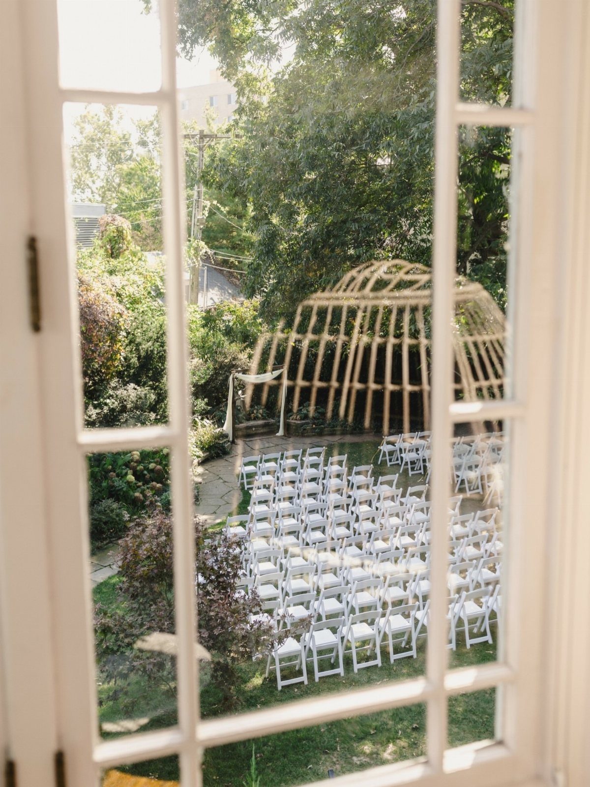 Outdoor wedding ceremony setup with white chairs and a wooden dome structure.