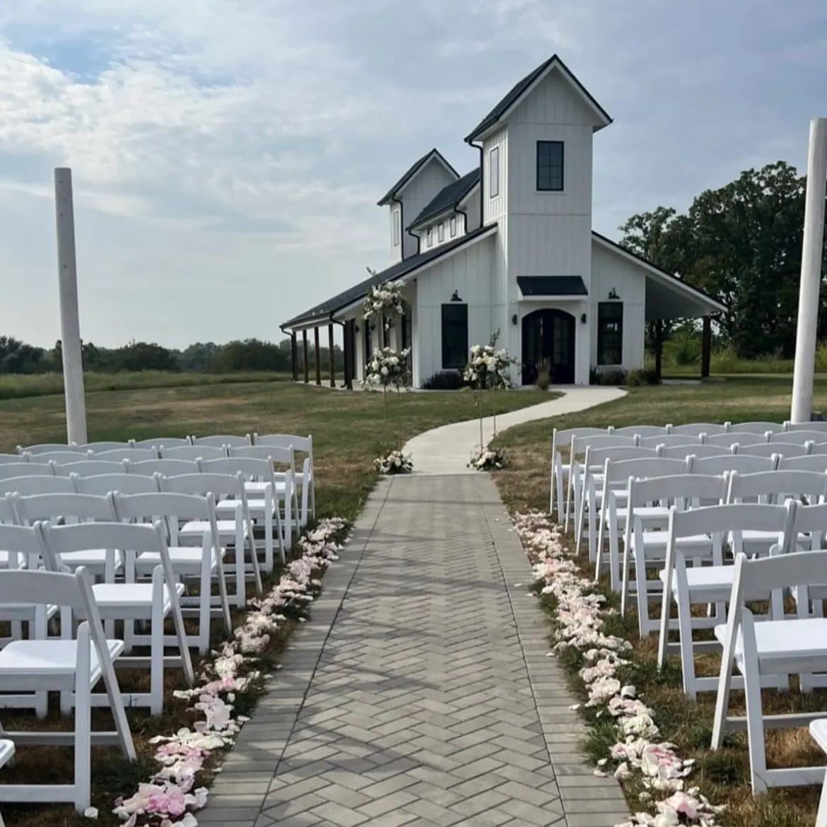 White folding chairs and a brick aisle leading to a white wedding chapel.