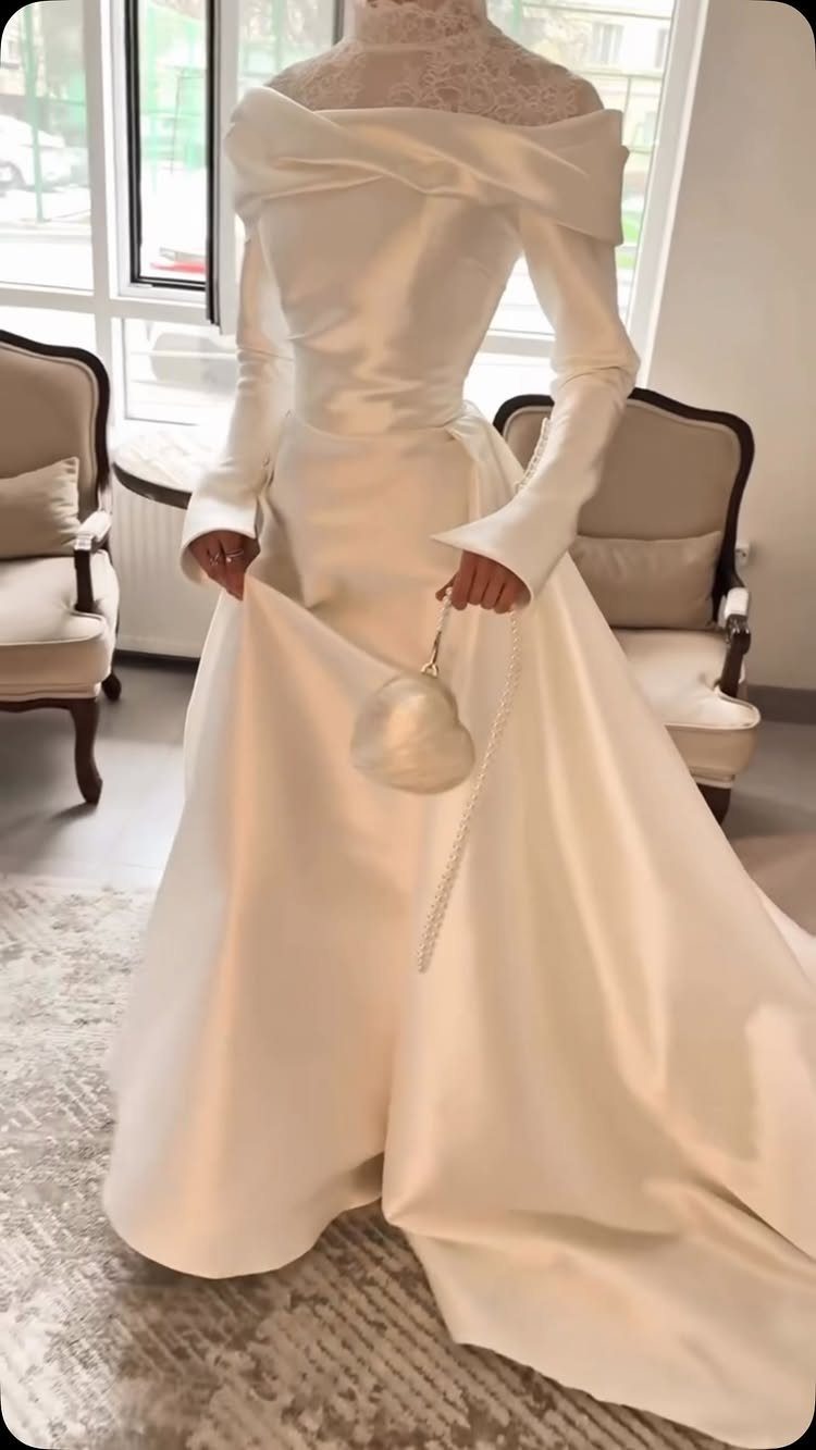 Woman wearing a modest white satin wedding dress with long sleeves and lace neckline