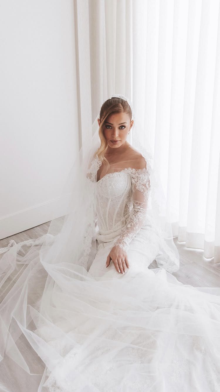 Woman in a white wedding dress with a lace bodice and long sleeves.