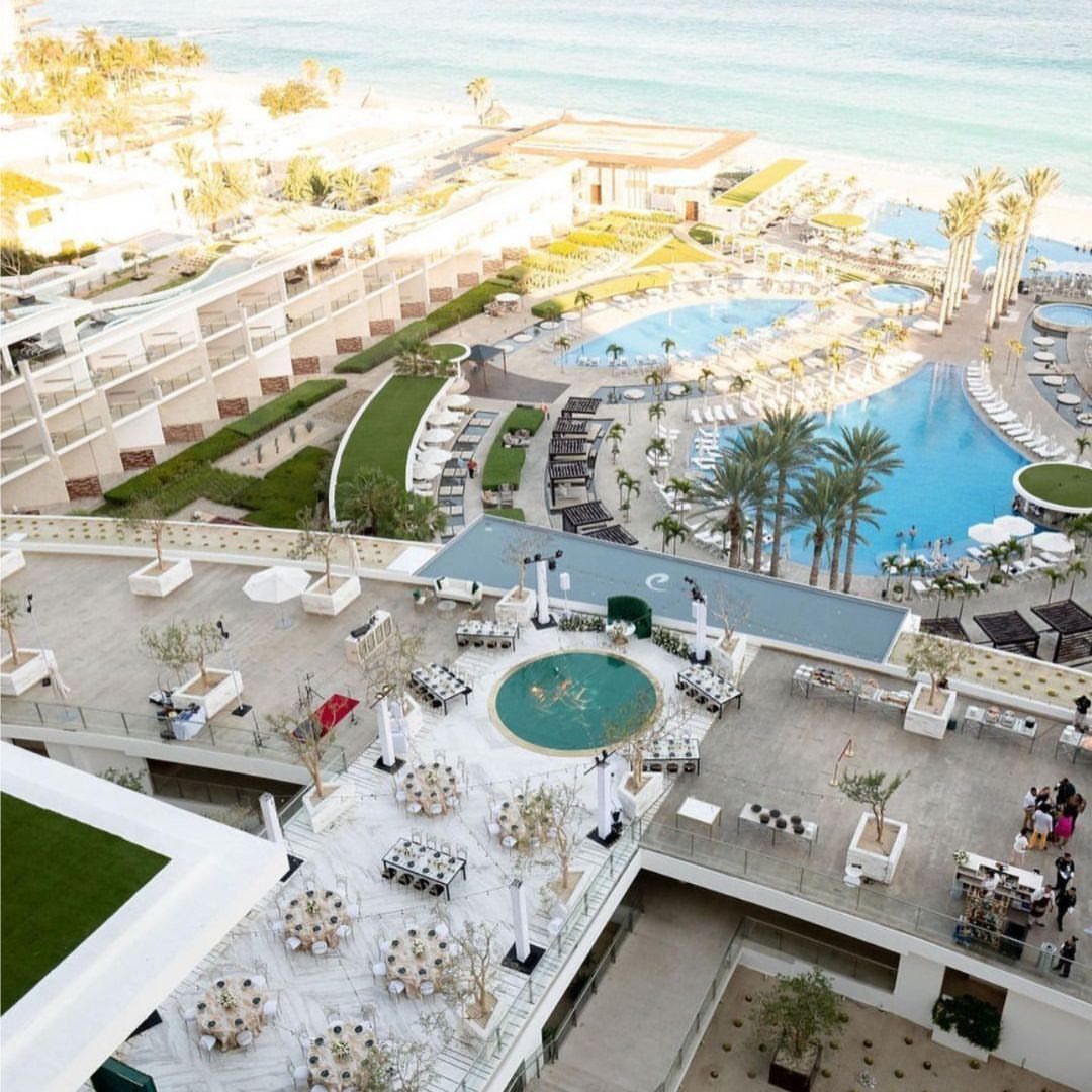 Luxury beachfront resort terrace with wedding table setups overlooking swimming pools and ocean.