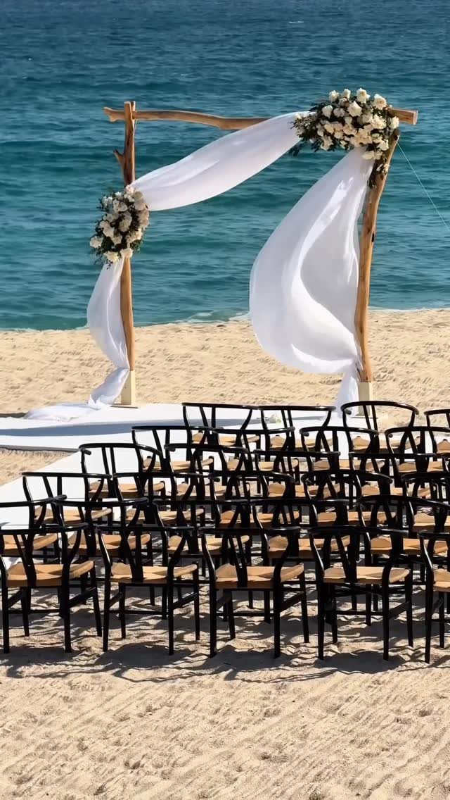 Wooden wedding arch with white fabric and flowers on a sandy beach
