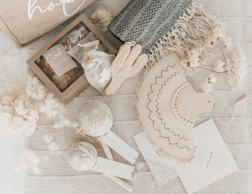 Wedding favors and accessories including a straw hat, woven blanket, and gift boxes.