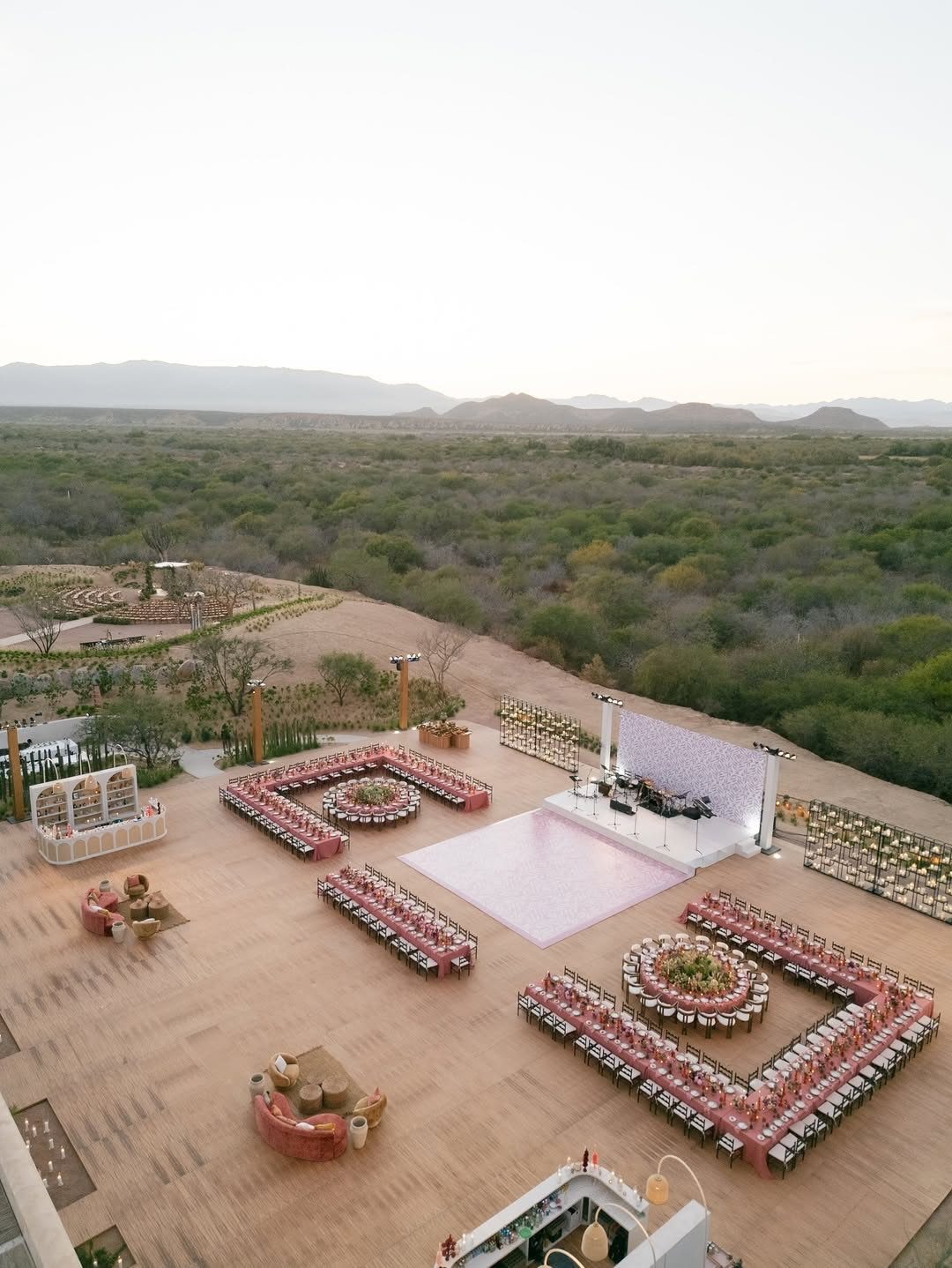 Luxury outdoor wedding reception setup with pink chairs and a white dance floor.