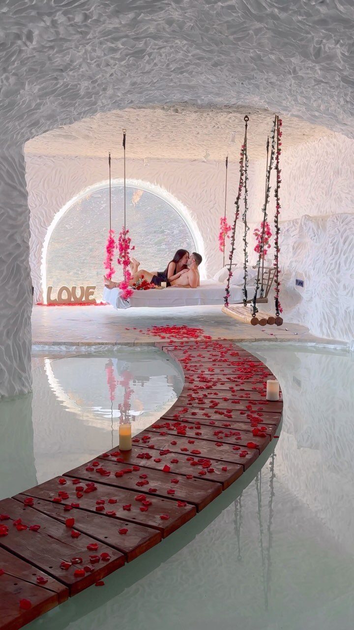Couple kissing in a white cave room with rose petal walkway and pool