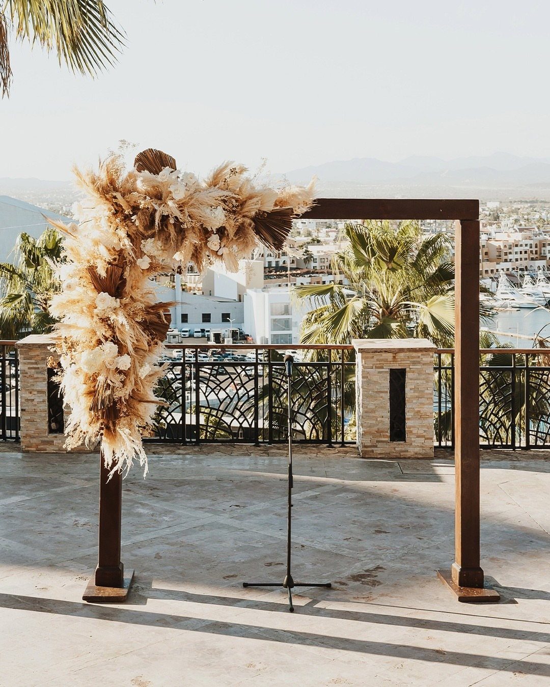 Wedding arch with pampas grass on a terrace overlooking a coastal town.