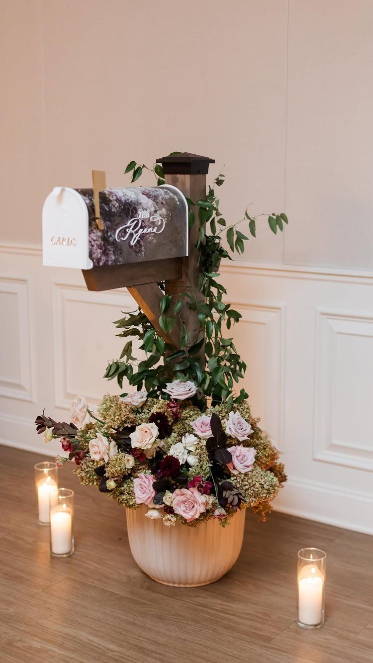 Floral patterned mailbox on a wooden post with roses and lit candles.