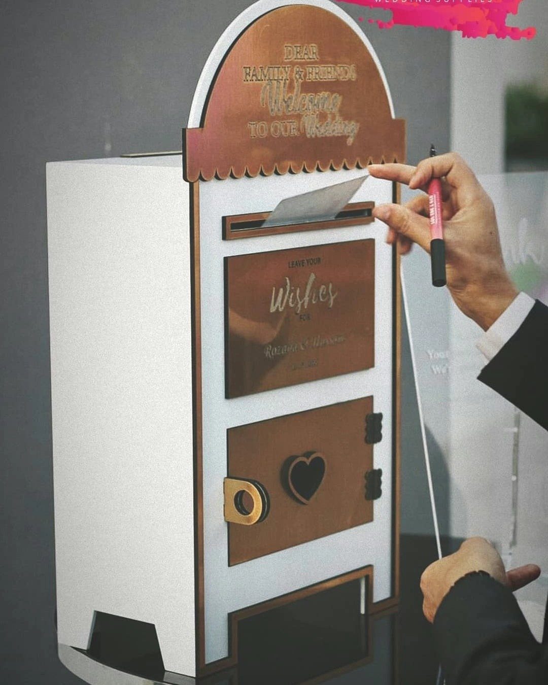 Decorative white and copper wedding mailbox with a person inserting a card.