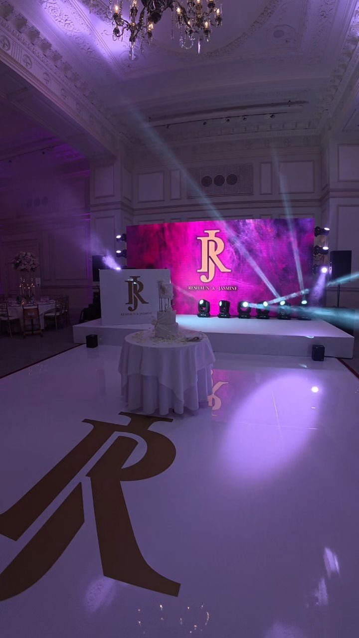 Gold monogram on a white dance floor with purple monogram lighting in background
