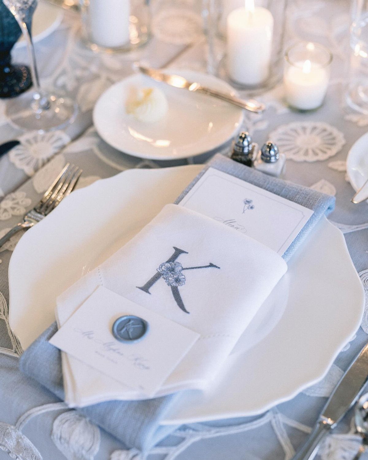 White cloth napkin with a grey monogrammed letter K on a wedding table.