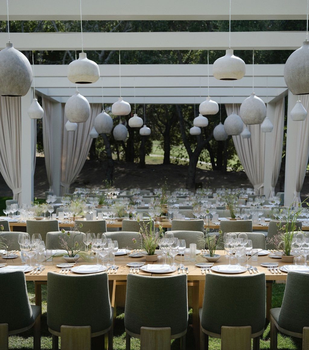Outdoor wedding reception tables under a white pergola with spherical hanging lights