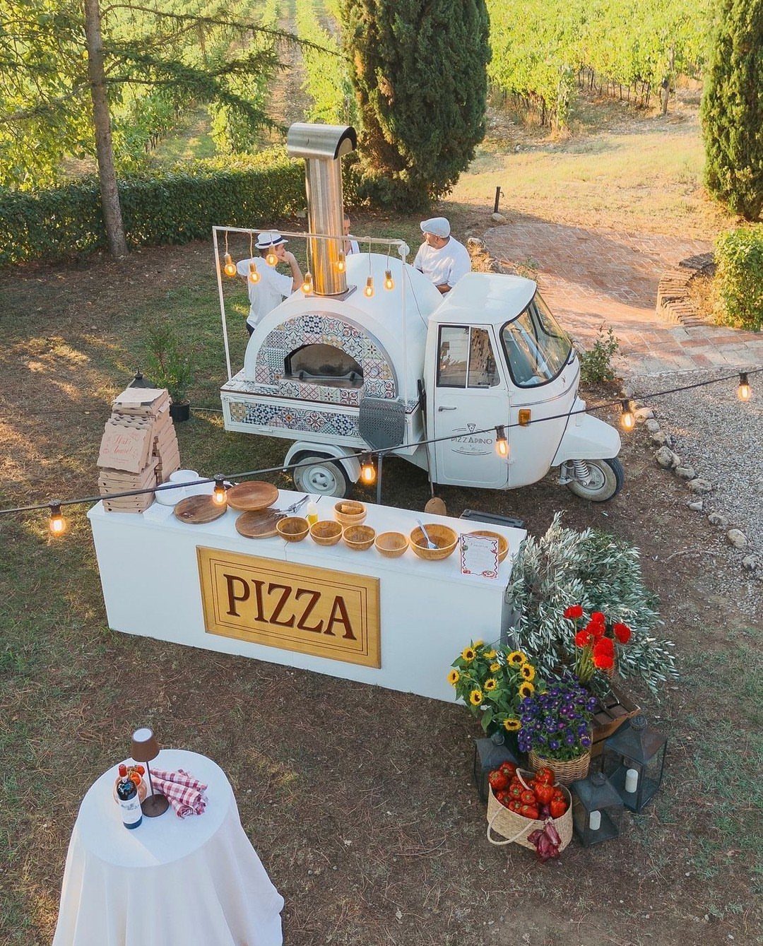 White vintage pizza food truck with chefs serving food in a vineyard setting