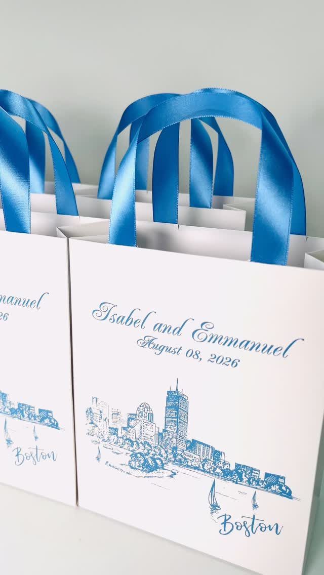 White gift bags with blue handles and personalized wedding text and Boston skyline.