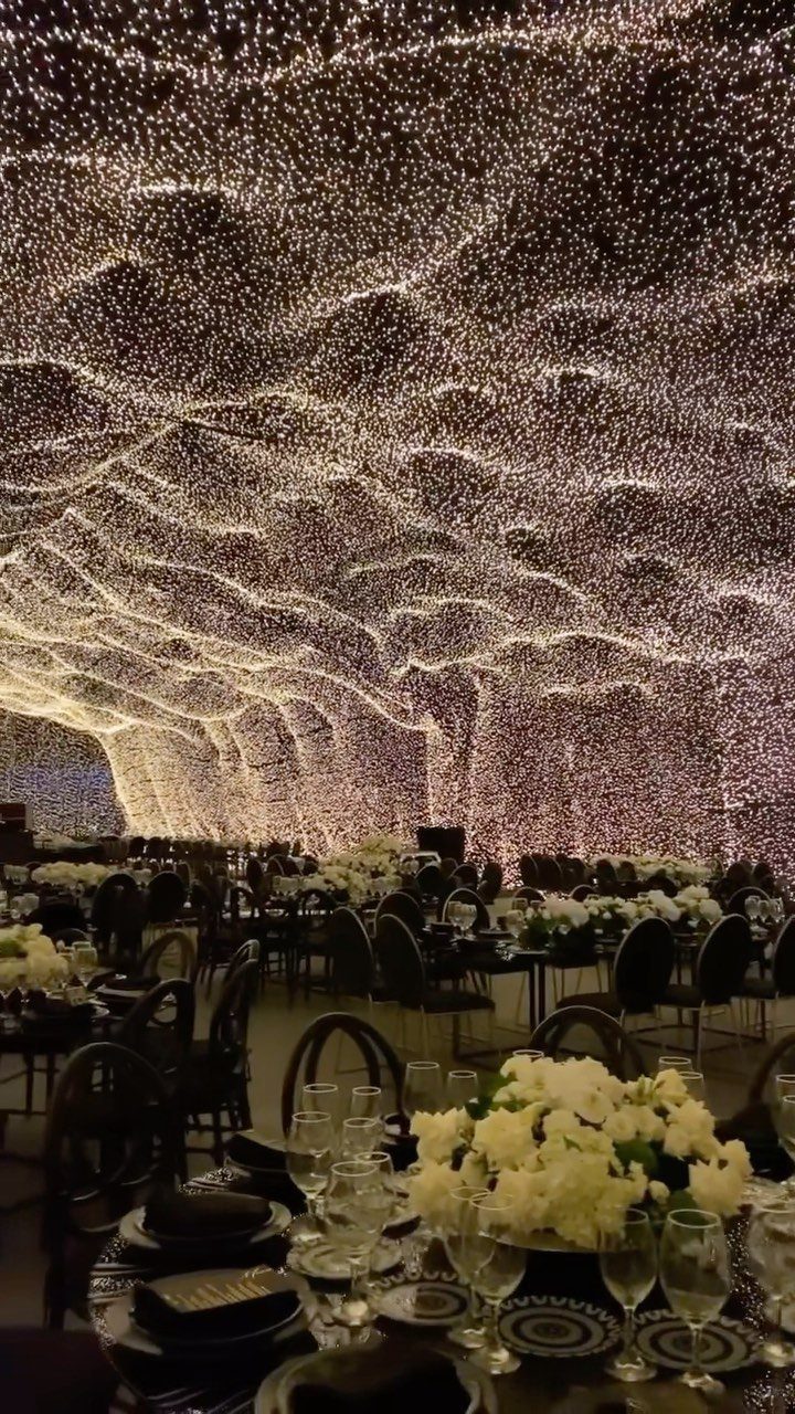 Wedding reception venue with a ceiling covered in shimmering warm white fairy lights.