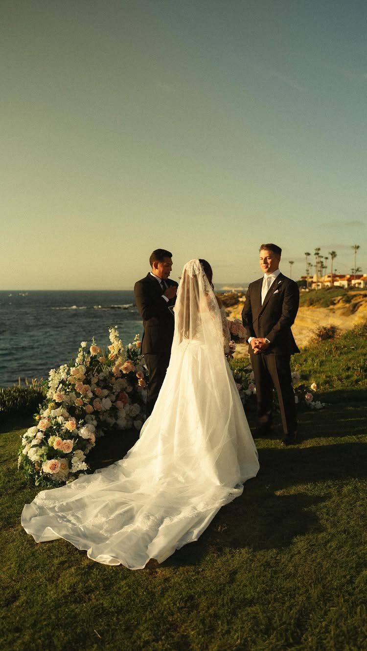 Bride and groom standing before an officiant during an intimate seaside wedding ceremony.
