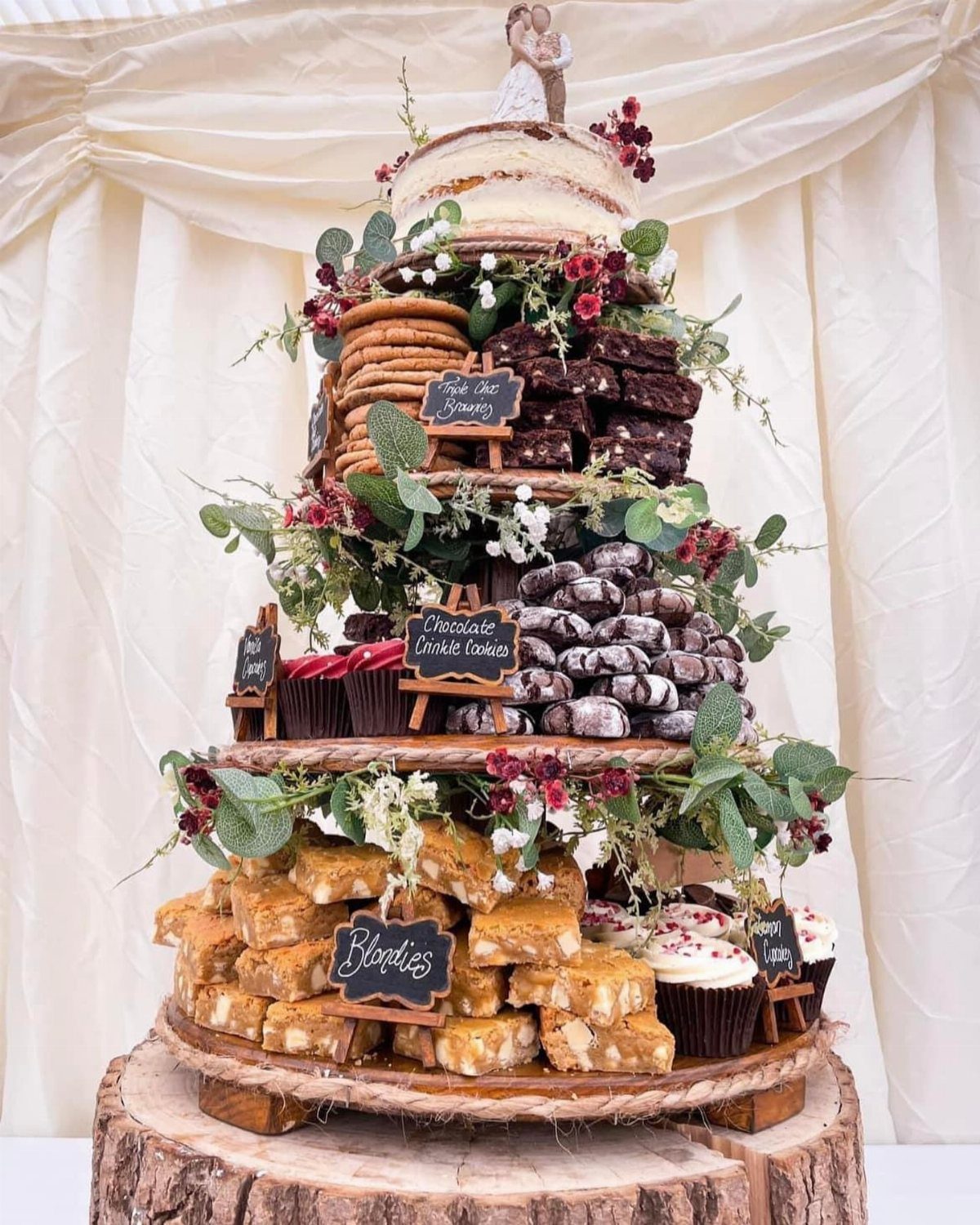 Tiered dessert tower with brownies, cookies, and cupcakes on a rustic wooden base.
