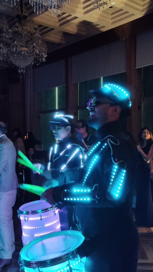 LED drummers in glowing blue uniforms performing at an indoor event venue.