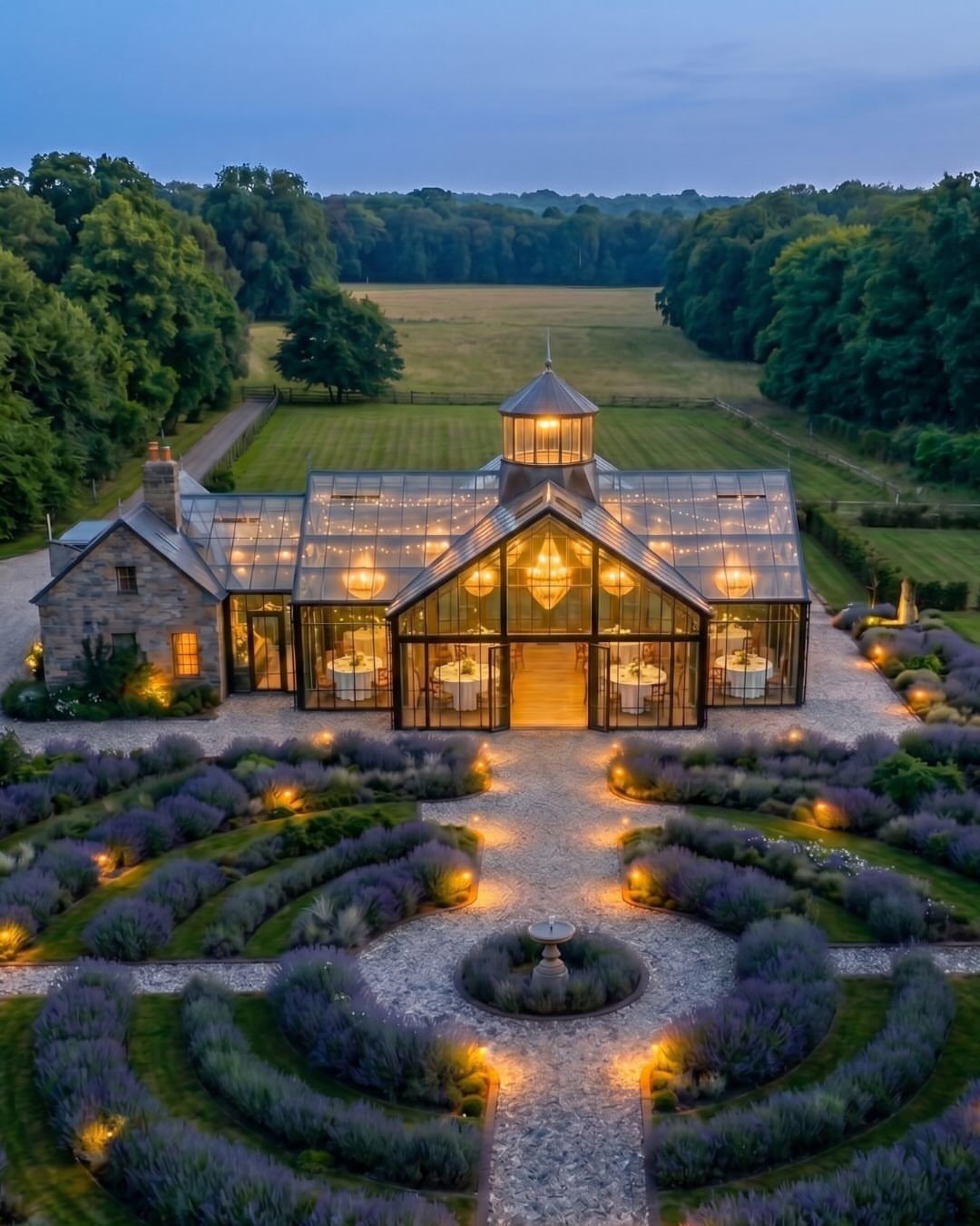 Glass greenhouse wedding venue surrounded by purple lavender gardens at dusk