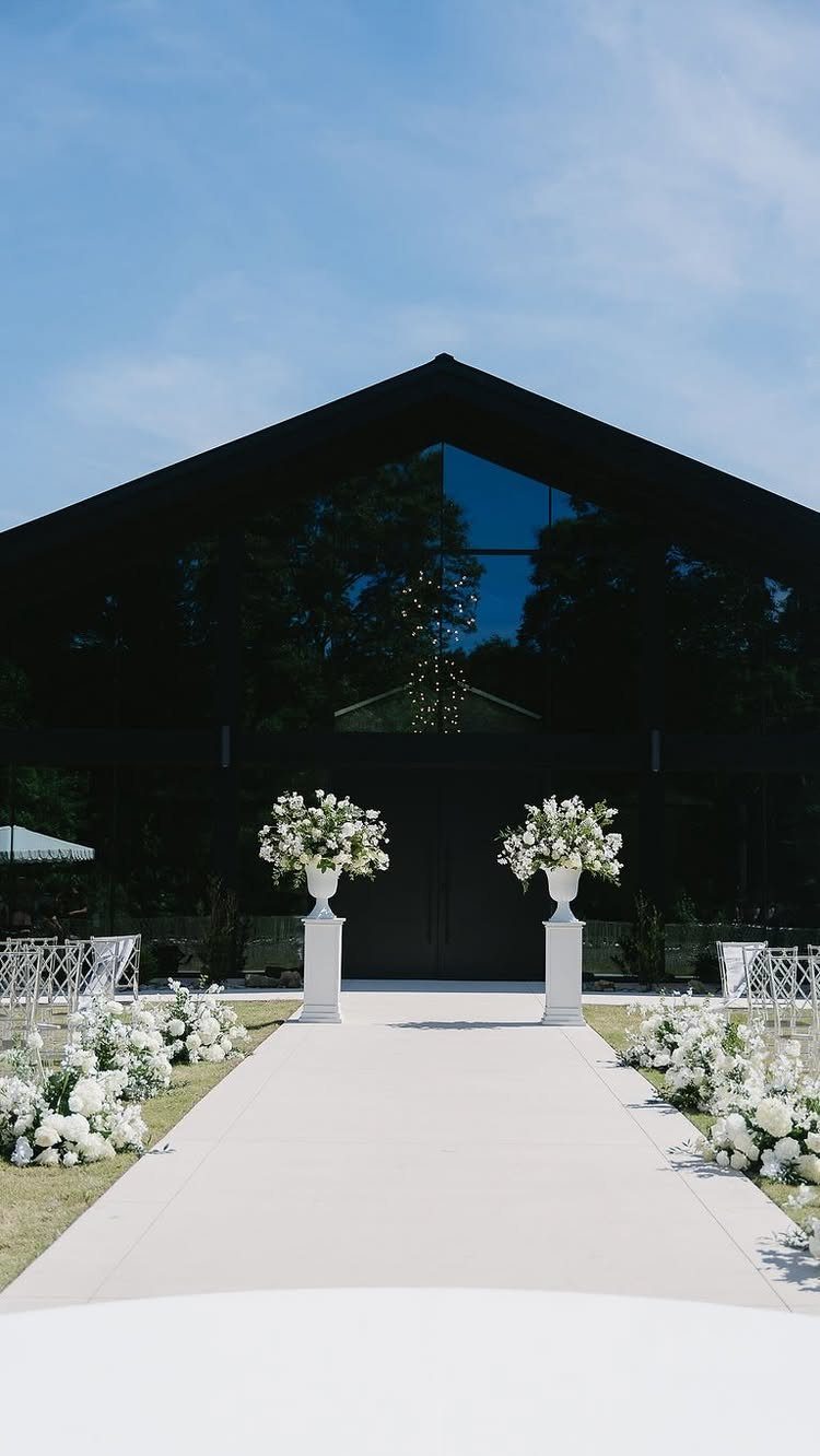 White wedding aisle with floral arrangements leading to a modern black venue