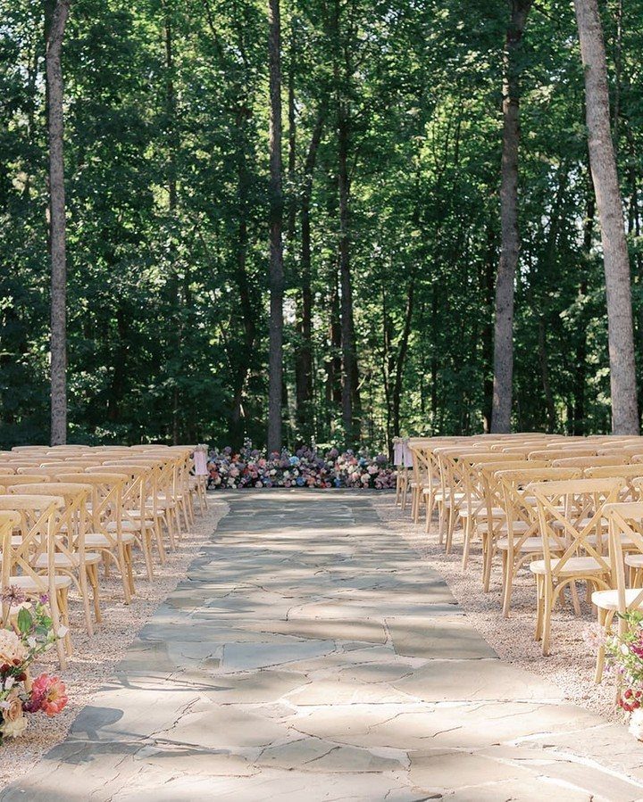 Wooden chairs lining a stone path for an outdoor forest wedding ceremony