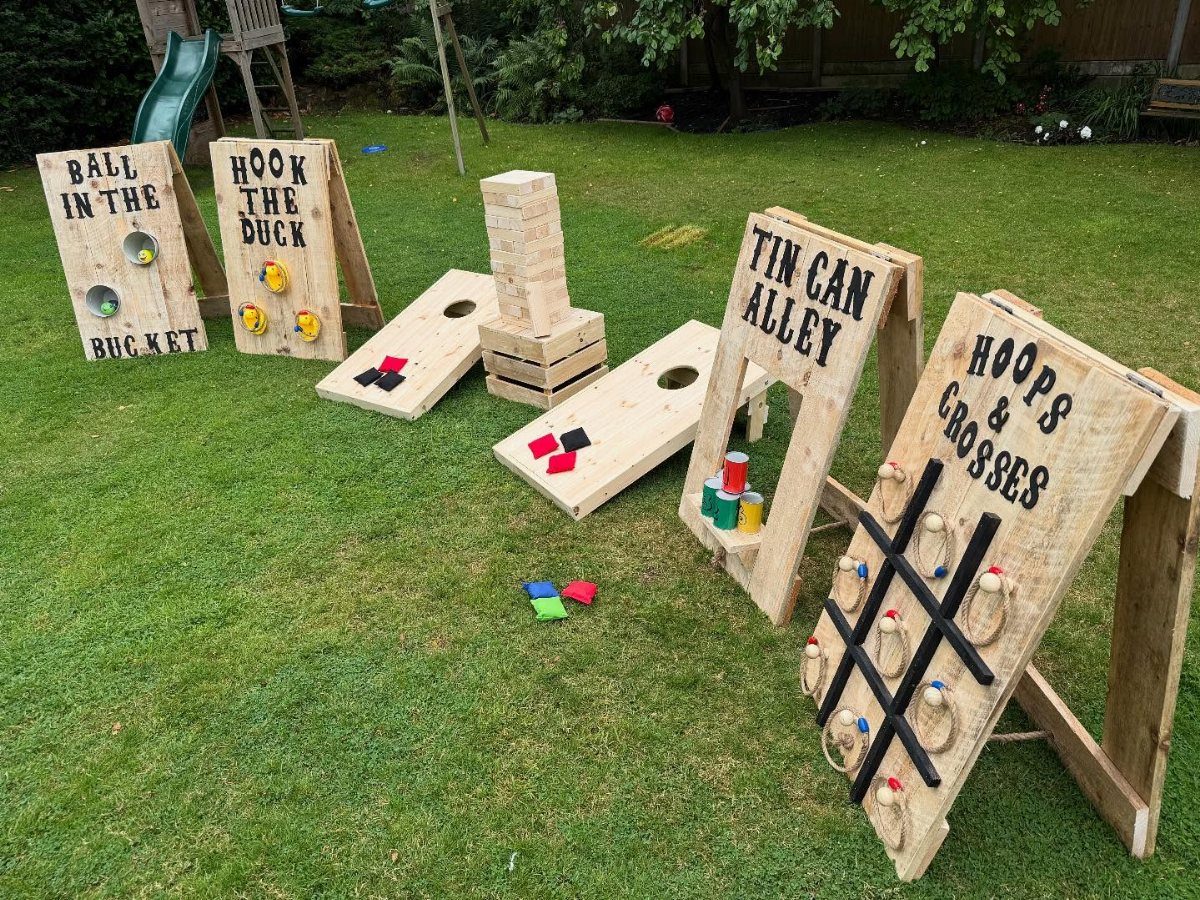 Wooden outdoor lawn games arranged on a green grass field for a party.