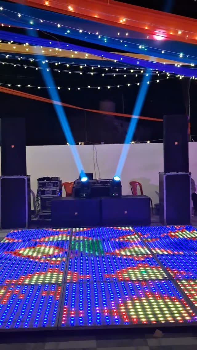Colorful LED dance floor with blue spotlights and festive overhead fabric decorations.