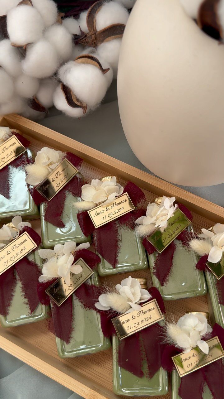 Green soaps with burgundy ribbons and gold name tags in a wooden tray