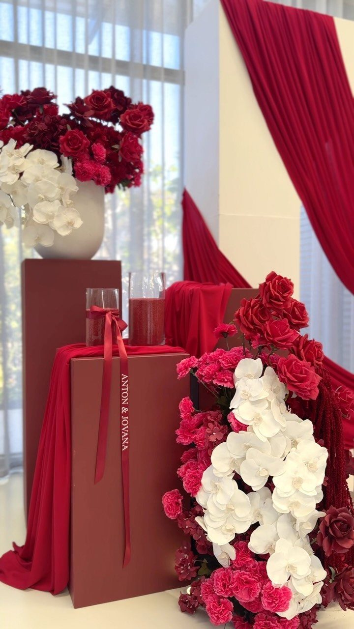 Red and white floral arrangements with red fabric drapes for an engagement party.