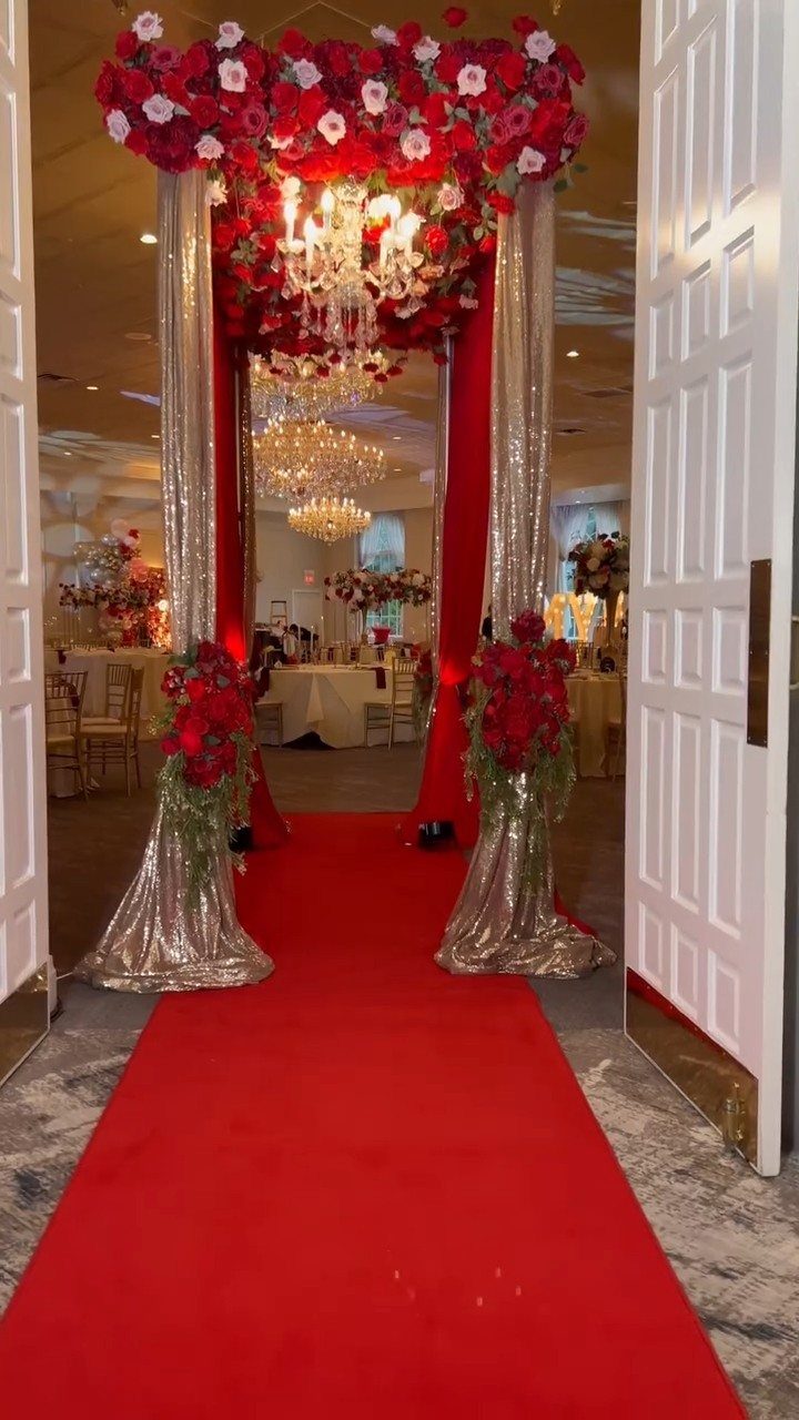 Red carpet entryway with silver sequined pillars and a red floral archway.