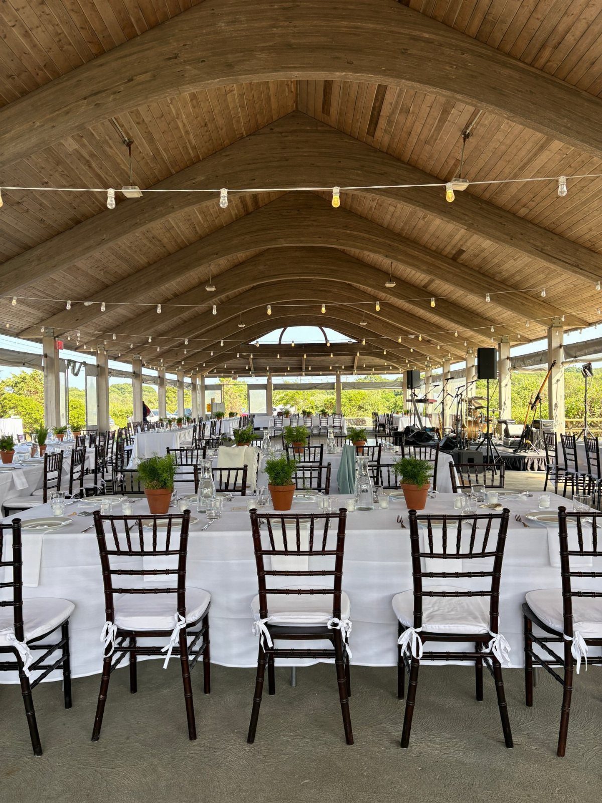 Wedding reception tables with white linens and dark wooden chairs under a vaulted ceiling