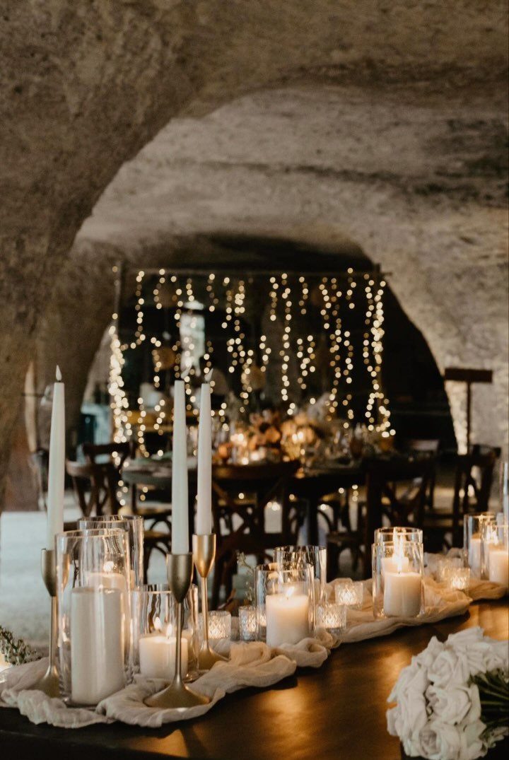 Wedding reception table with white candles and roses inside a lit stone cave