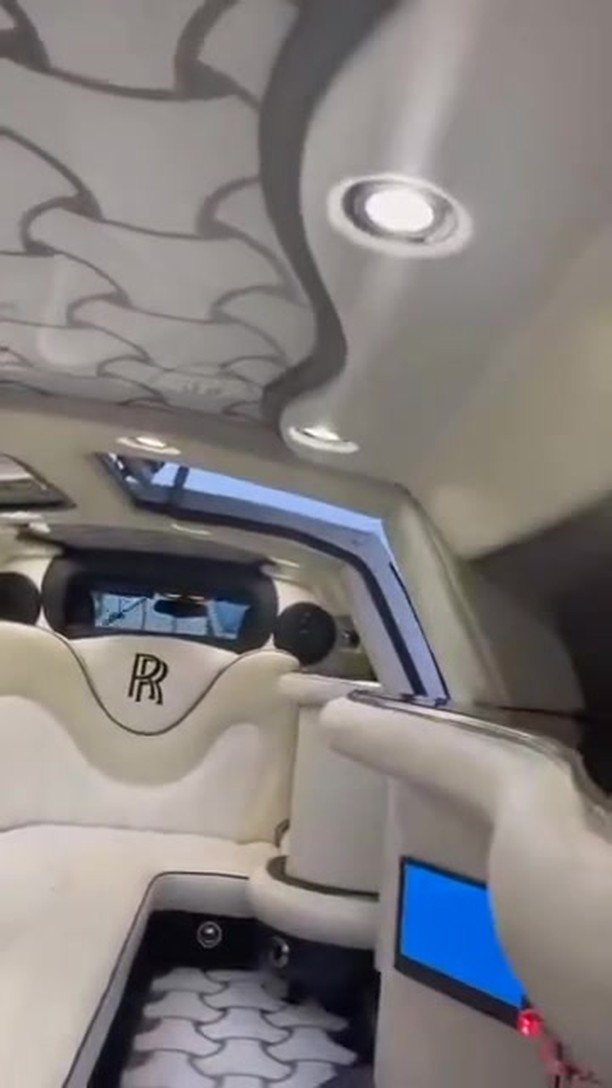 White leather car interior with RR logo and patterned ceiling lighting.