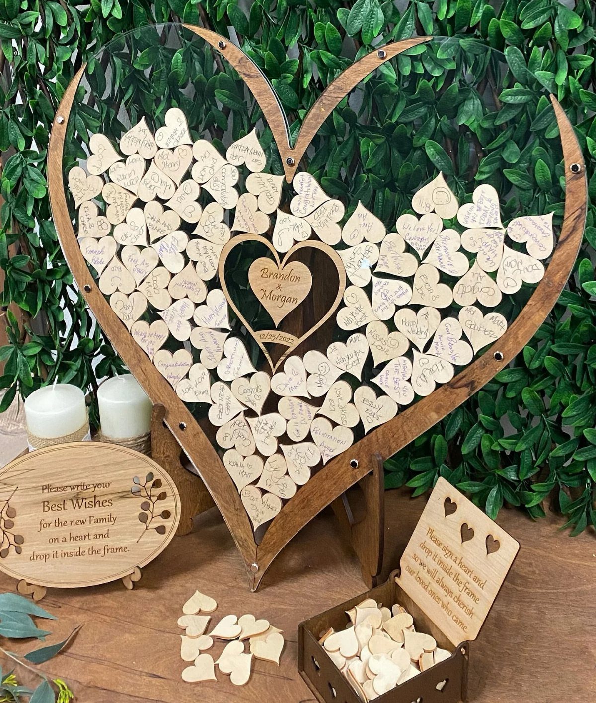 Heart-shaped wooden guest book frame filled with small wooden heart tokens and messages.