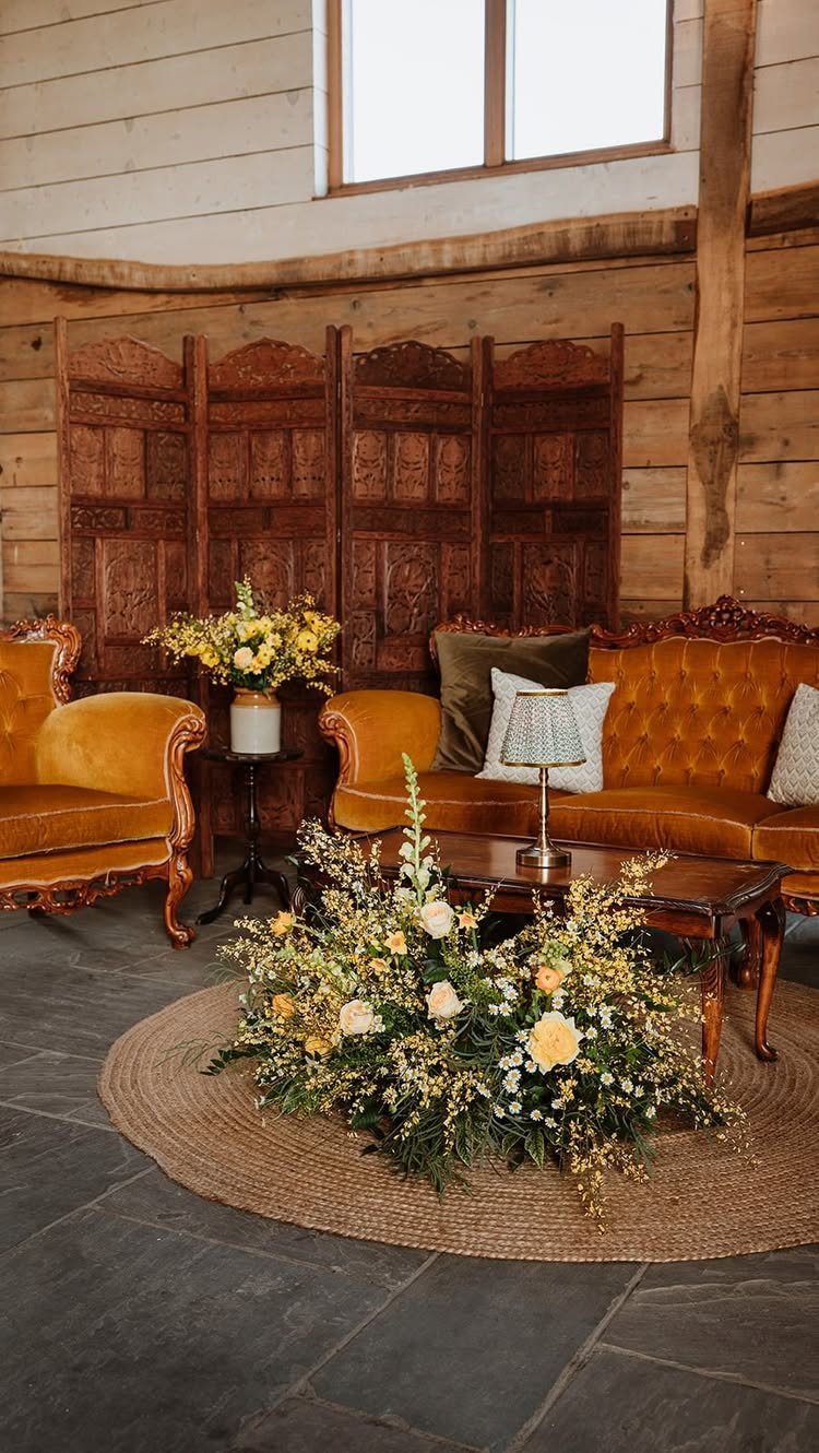 Vintage brown leather sofa and armchair in a rustic wooden barn lounge area.