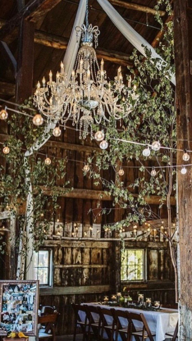 Crystal chandelier and string lights hanging in a rustic wooden barn wedding venue