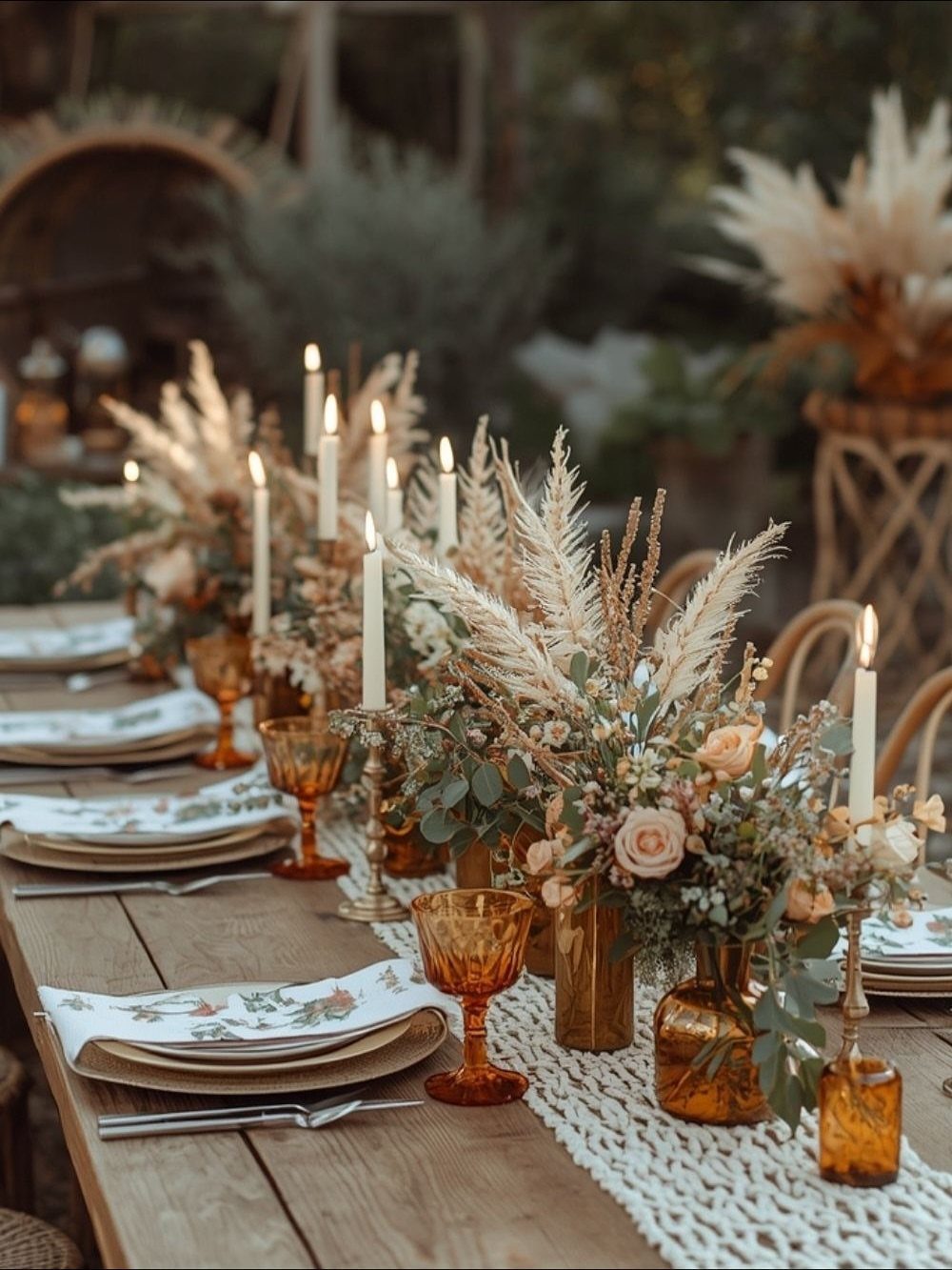 Wooden wedding table with amber glasses, white candles, and pampas grass floral arrangements.