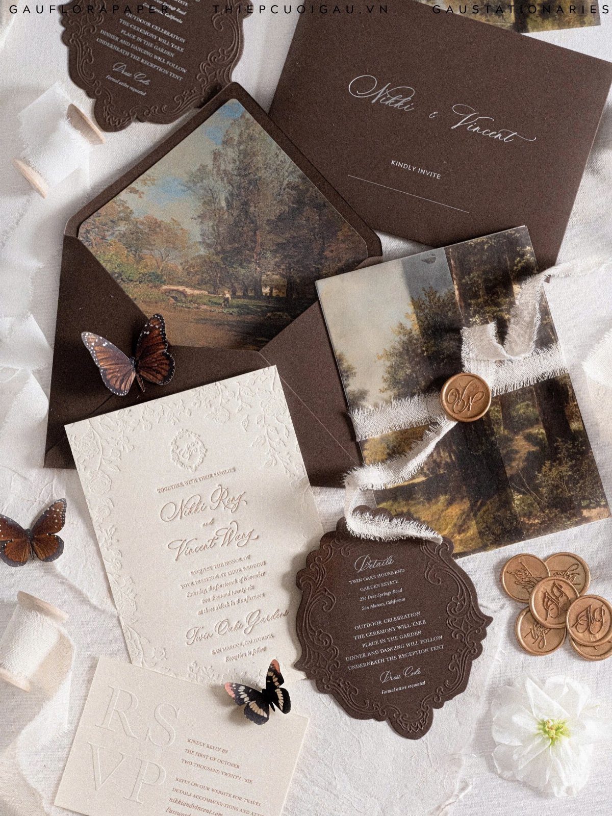 Wedding invitation suite with brown envelopes, cream cards, wax seals, and landscape art.