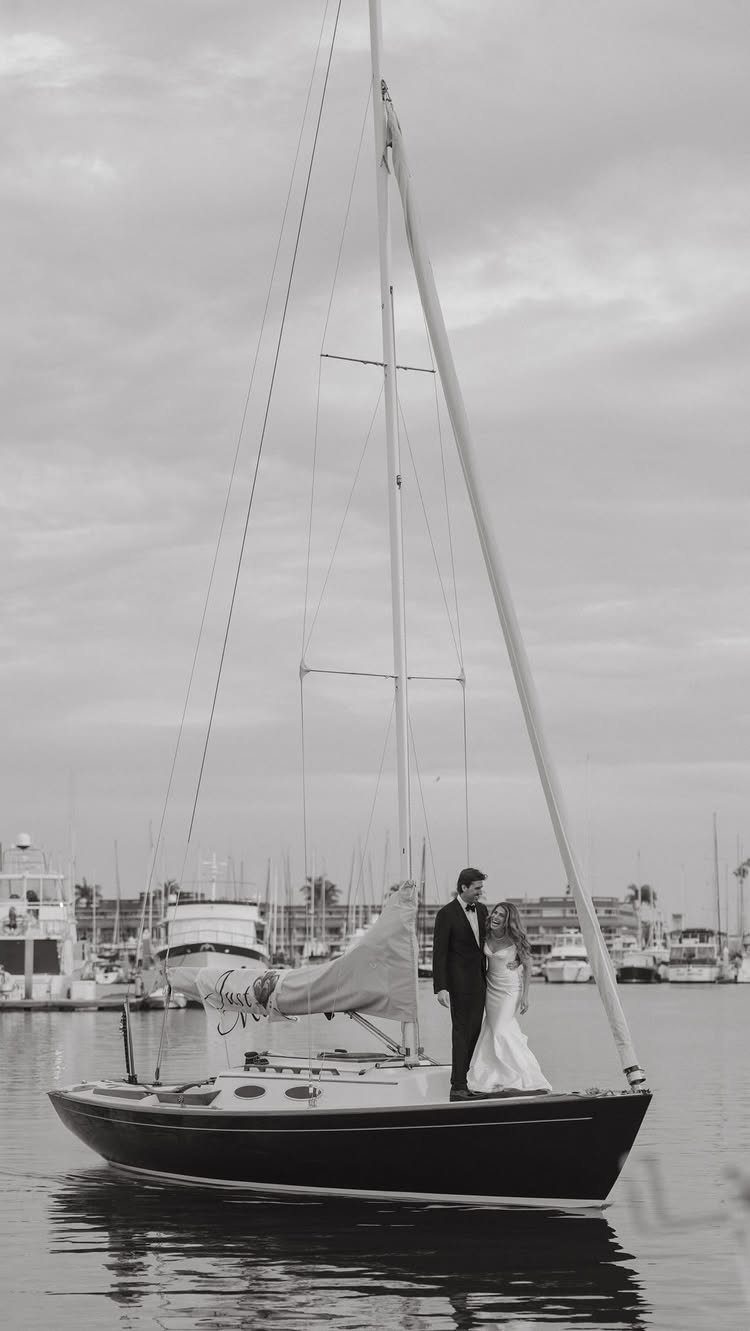 Bride and groom standing on a sailboat in a harbor for their wedding.